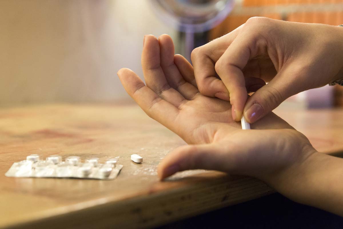 A man places a pill in his hands and wonders about the effects of stimulant abuse
