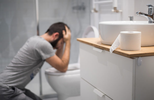 A man prepares to vomit into a toilet as he goes through cocaine withdrawal symptoms
