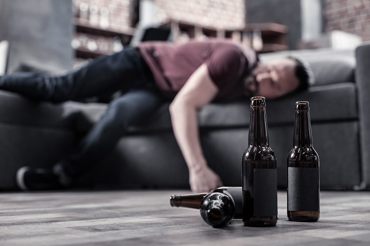 A man lays on the couch and wonders is alcoholism a disease
