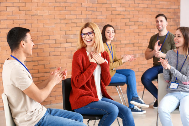 a group applauding someone making a breakthrough as a benefits of group therapy