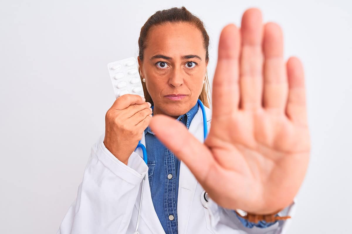 doctor using hand to stop someone from taking pills how to stop drug abuse