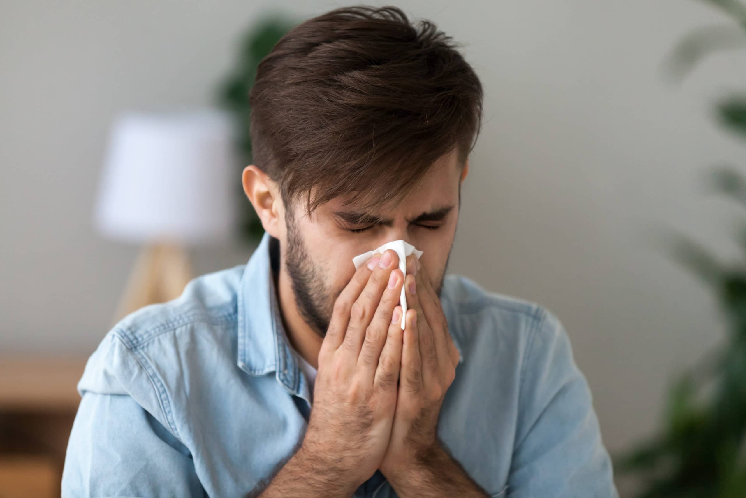 man with a compromised immune system sneezing because he probably has coronavirus
