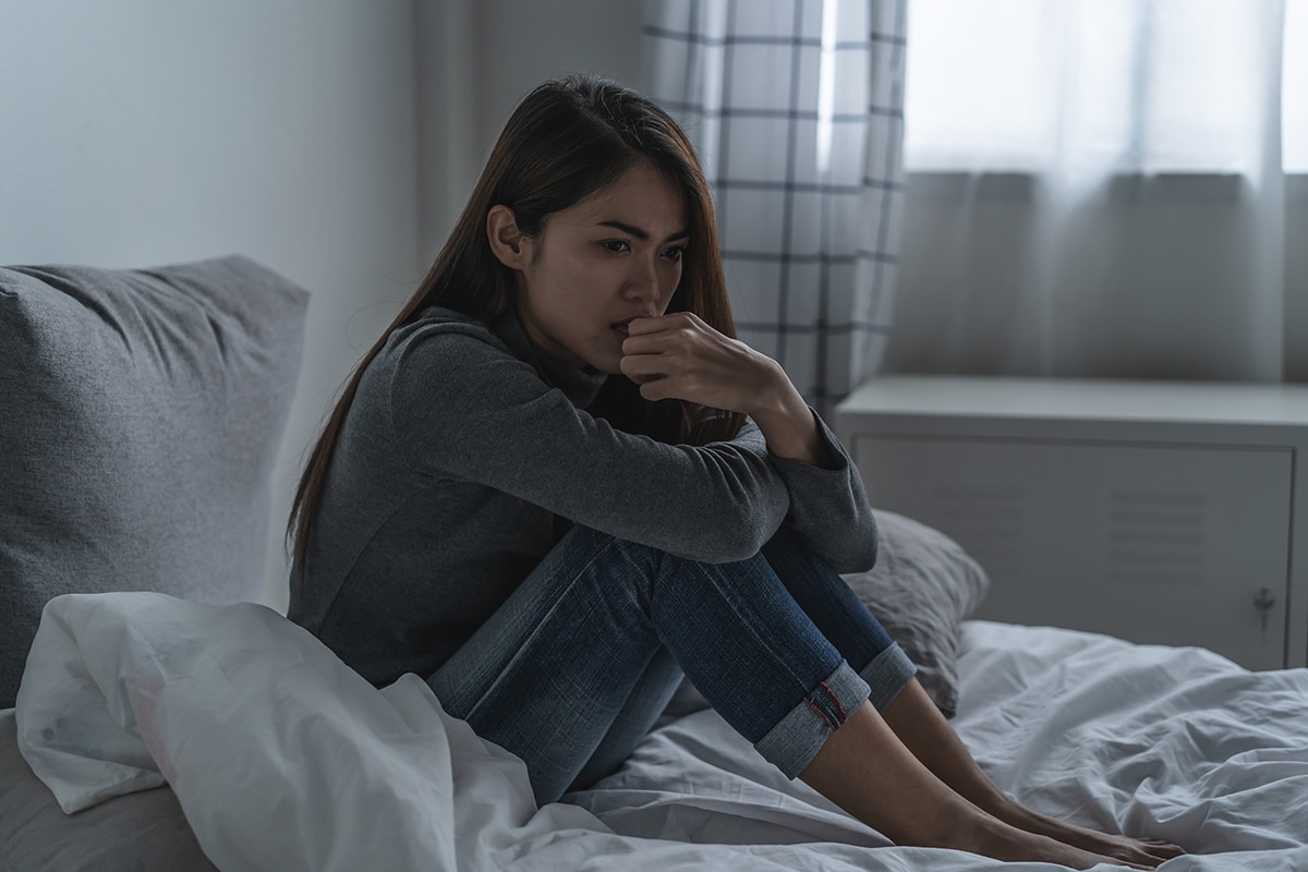 woman holding knees to chest on her bed thinking about the brain and depression