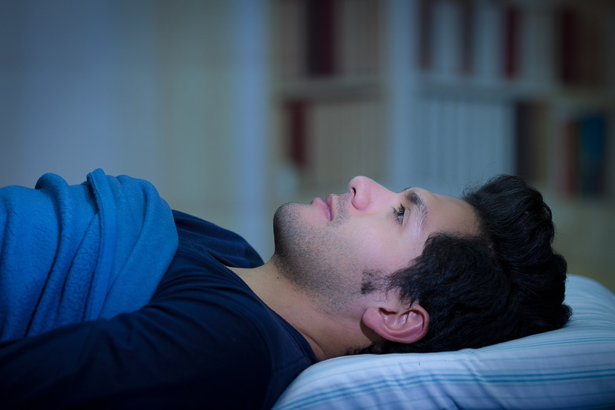 man in bed worried about triggers of an anxiety attack