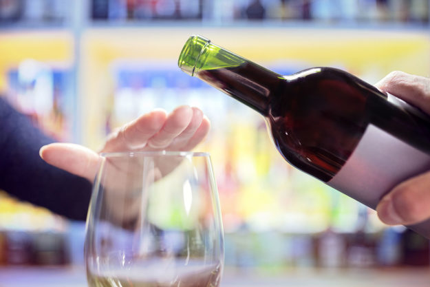 hand covering glass preventing wine from being pour because of detoxing from alcohol