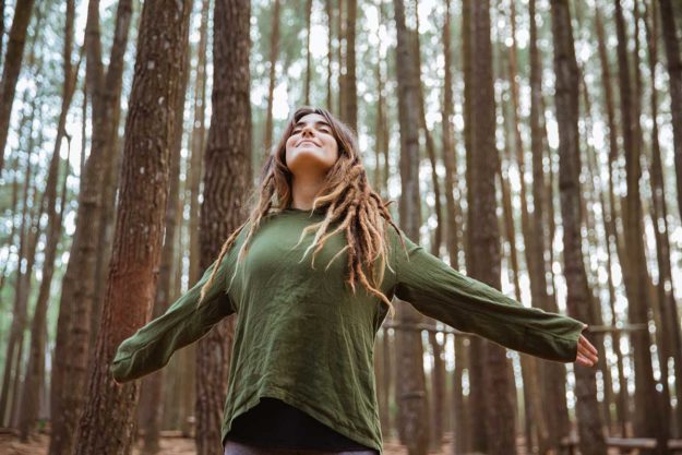 woman with arms wide in forest living life in recovery