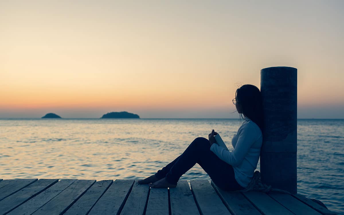woman sitting on pier prioritizing your recovery goals