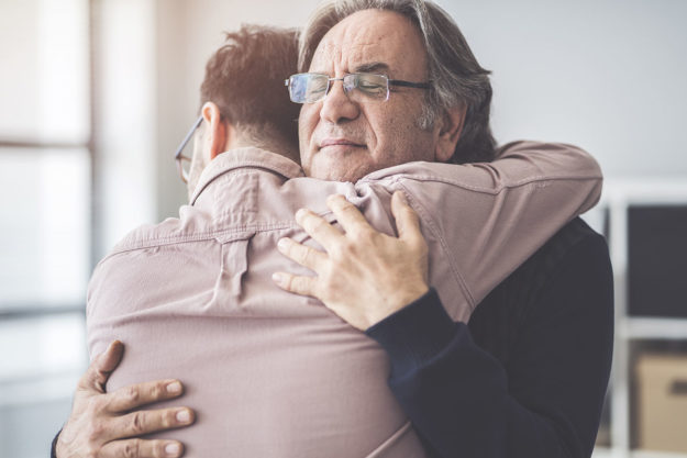 two men hugging as part of a support system for recovery