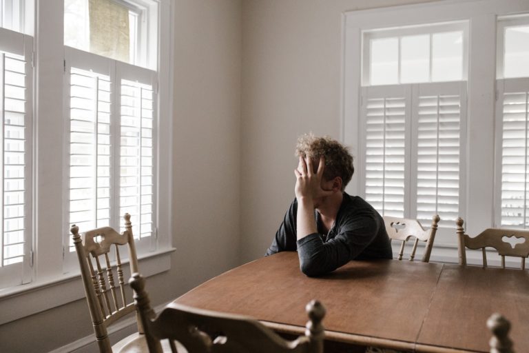 person sitting alone at a table reflecting on the biological effects of alcohol