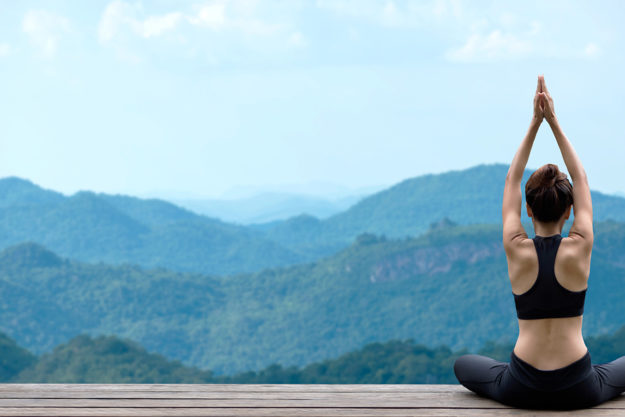 woman doing yoga facing hills as part of her relapse prevention techniques