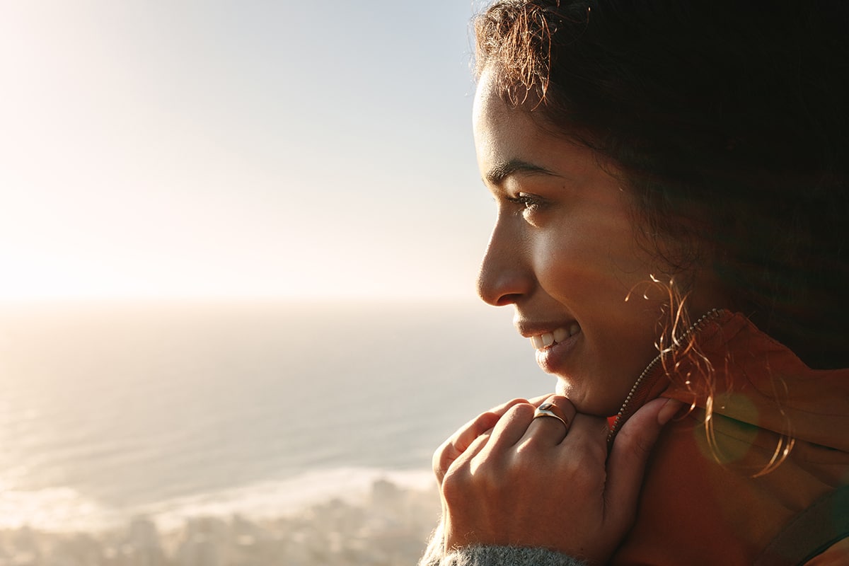woman smiling looking out over ocean having a sober summer