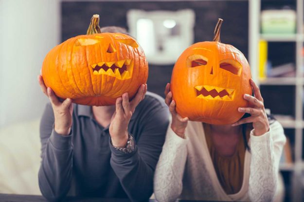 two people holding up pumpkins for halloween