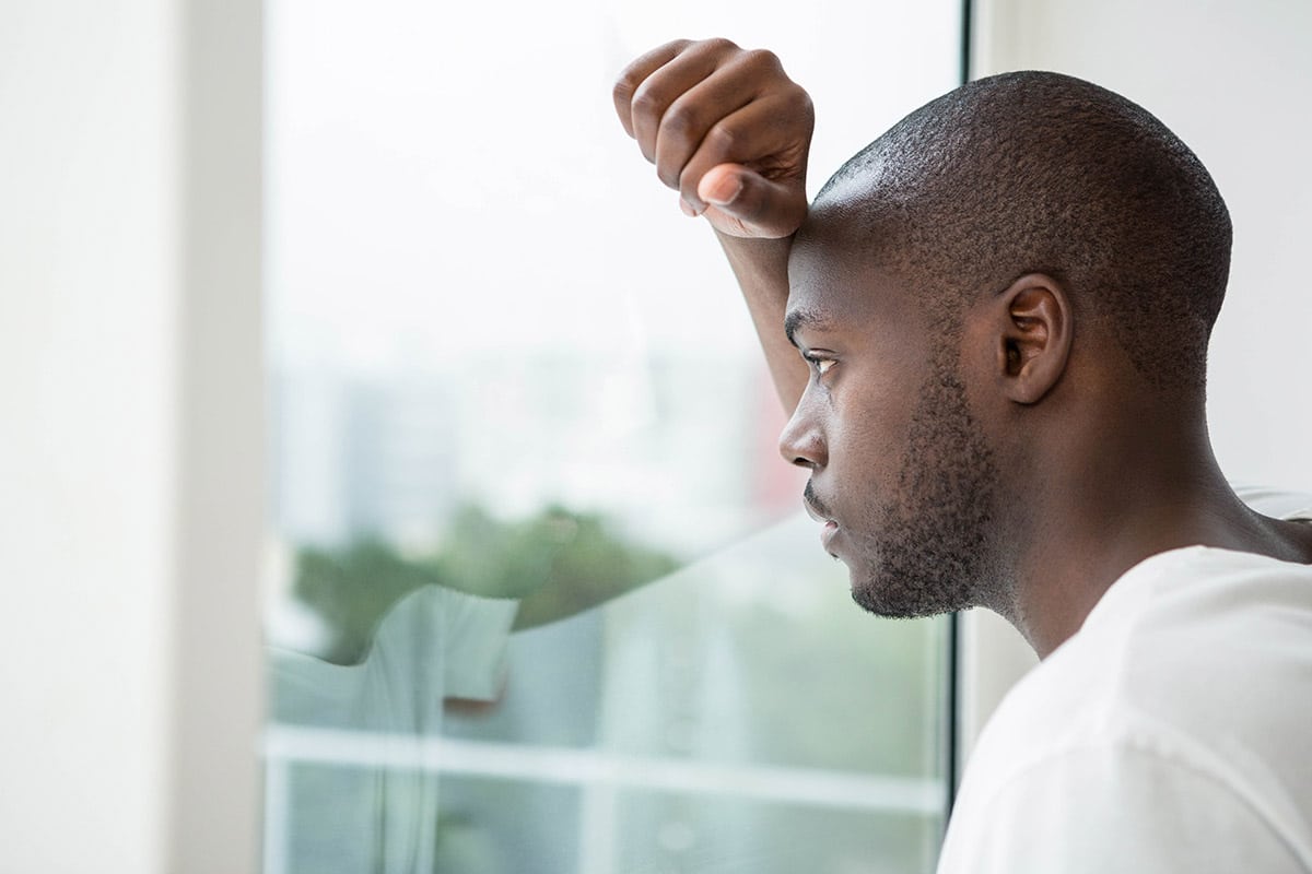 man looking out window wondering about recovery