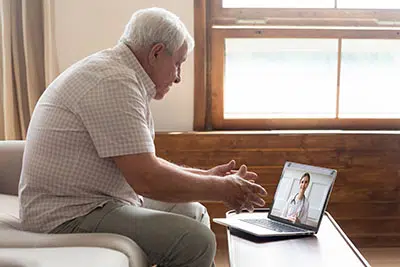 older man using laptop for telehealth intensive outpatient program