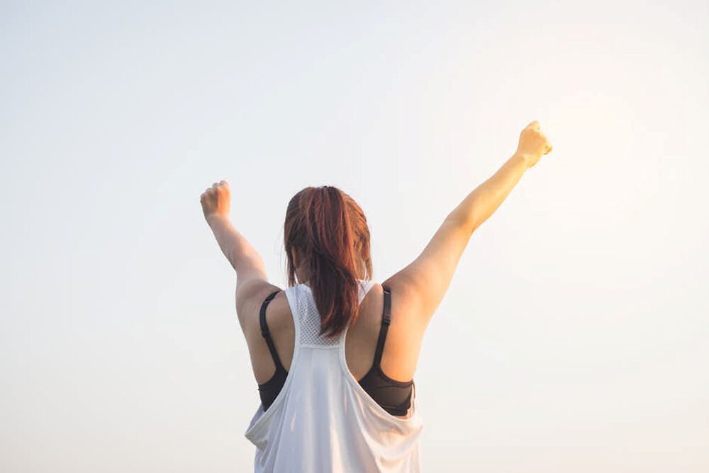 person raising their arms in celebration while learning how to stop binge drinking