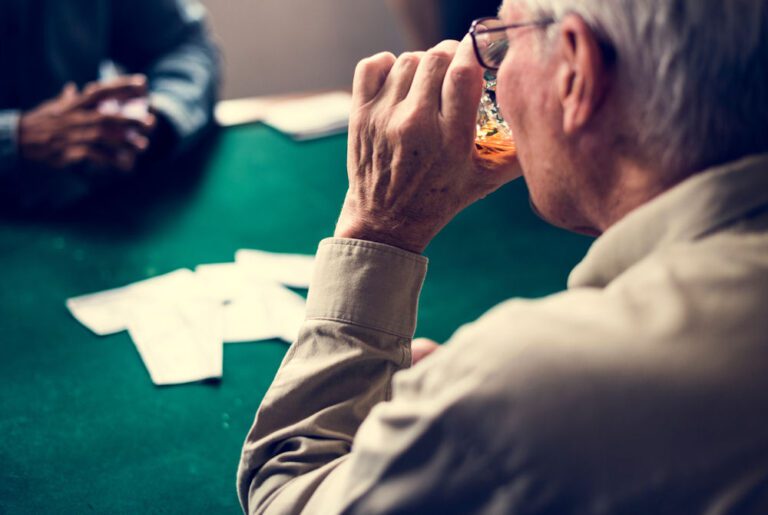 older man drinking alcohol while gambling, wondering does abilify cause gambling addiction