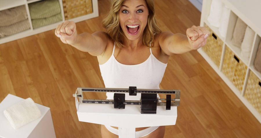 Happy woman on a scale after losing weight with Naltrexone