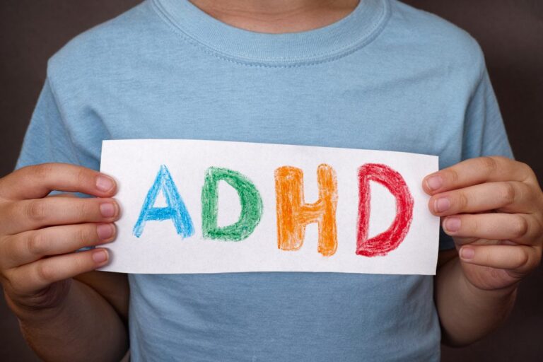 child holding a colorful adhd sign illustrating how adhd and alcohol are connected