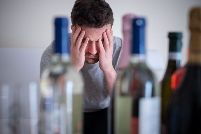 guy distressed surrounded by alcohol showing anger and aggression issues