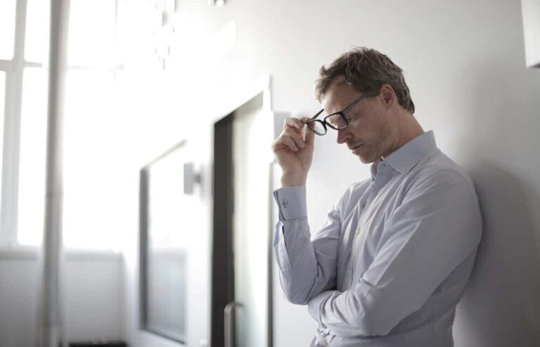 man in light shirt in a thoughtful pose considering how to deal with a mean drunk