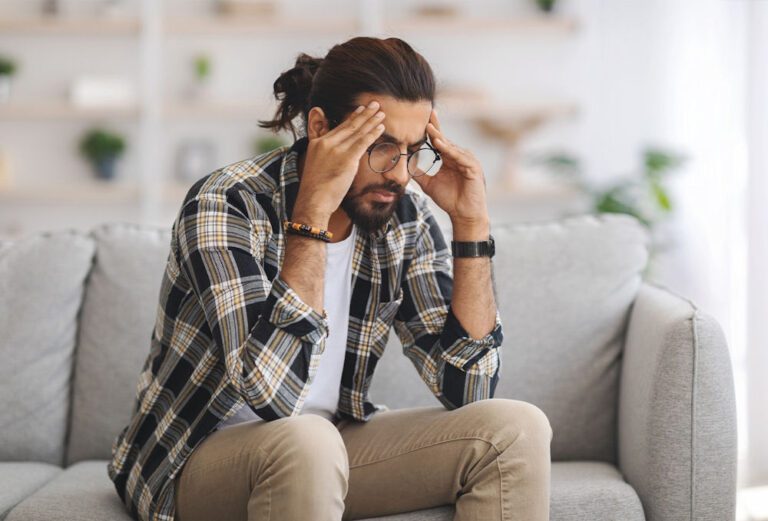 man sitting looking stressed and worried while dealing with hangover anxiety