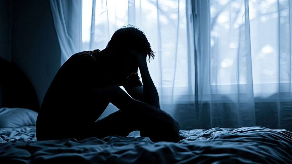 Young man alone on bed struggling with men's mental health stigma