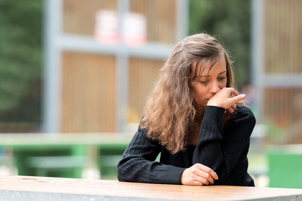 girl sitting at a wooden table considering treatment for Klonopin addiction