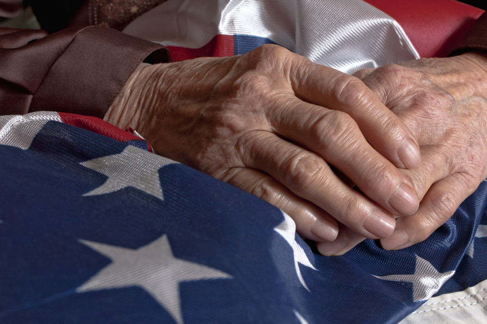 tricare-insurance-for-veterans-coverage Veteran’s hands resting on an American flag representing Tricare Insurance for Veterans.