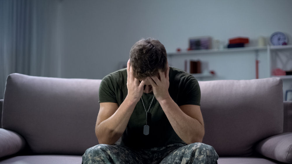 tricare-insurance-for-veterans-rehab-support Veteran sitting on a couch while seeking support through Tricare Insurance for Veterans.