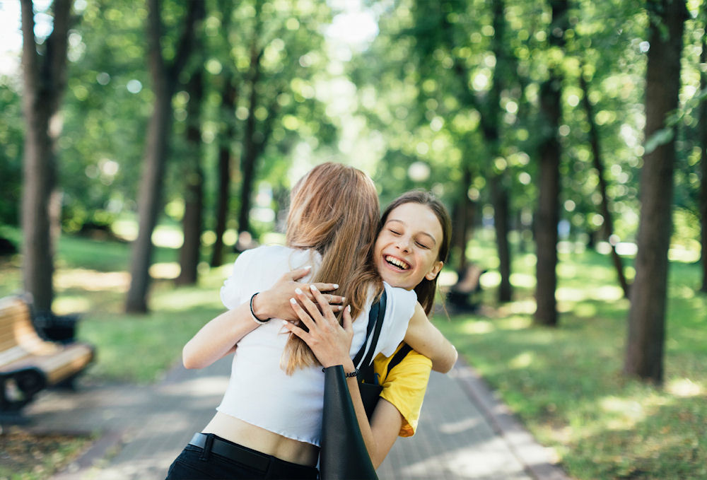 two teens girls hugging each other on a path outside
